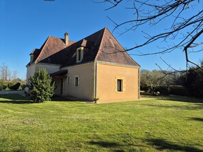 Una casa de dos pisos con techo inclinado y un pequeño jardín delantero.