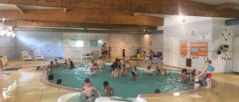 A swimming pool area with multiple pools, lounge chairs, and a covered seating area.