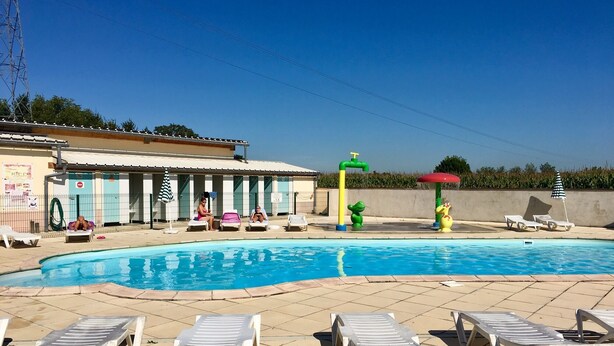 Ein Schwimmbecken mit Liegestühlen und ein Gebäude mit einem Ziegeldach.
