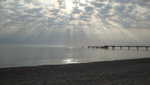 A beach with a pier extending into calm waters, under a cloudy sky. - family-friendly non-smoking house with large garden and beautiful view (Ralswiek OT Gnies)