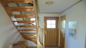 A wooden staircase leading to a door with a window. A small cabinet is on the left, and a rug is on the floor. - family-friendly non-smoking house with large garden and beautiful view (Ralswiek OT Gnies)