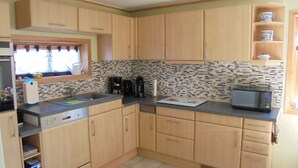 A compact kitchen with wooden cabinets, a microwave, a coffee maker, and a window with a view. - family-friendly non-smoking house with large garden and beautiful view (Ralswiek OT Gnies)