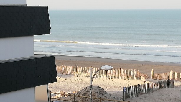 Une vue sur la plage avec une clôture en bois et un lampadaire.
