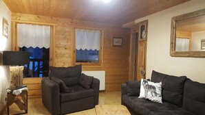 Une pièce chaleureuse avec deux canapés, un plafond en bois et une fenêtre avec des rideaux.