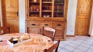 Un coin repas comprenant une table ronde, des chaises et un buffet en bois doté de portes en verre.