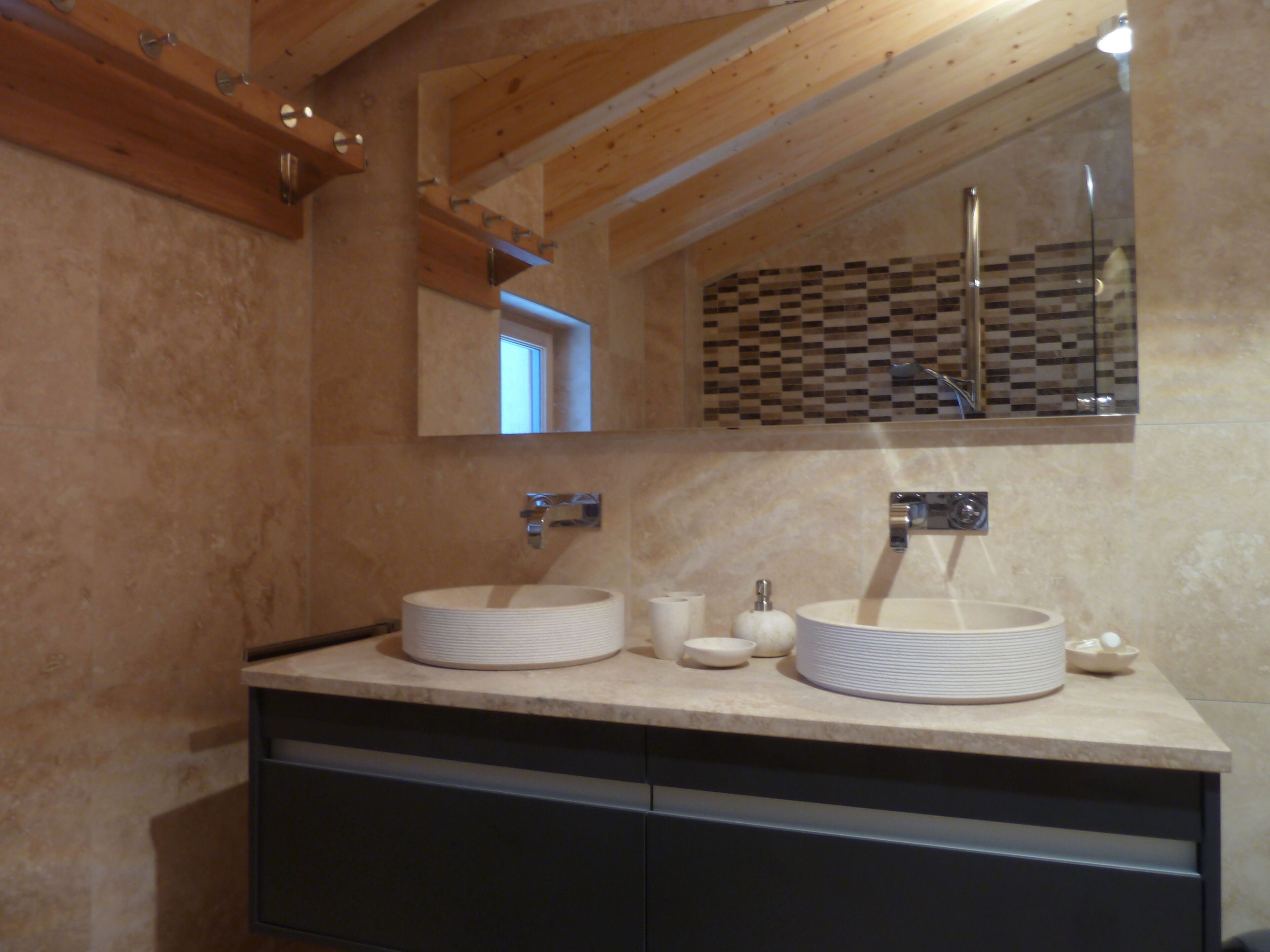 A modern bathroom with two round sinks, a mirror, and a tiled backsplash.