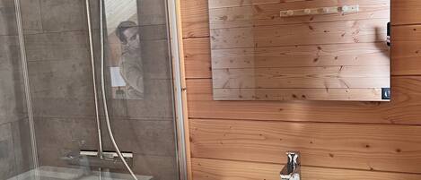 Une salle de bain moderne avec une douche à parois de verre, un lavabo blanc et un meuble-lavabo en bois.