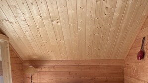 Een gezellig houten chaletinterieur met een bank, een klein tafeltje en een lamp.