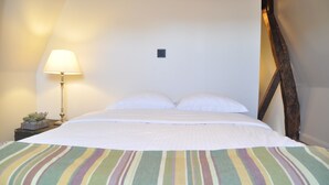 Een hotelkamer met een bed, een nachtkastje met een lamp en een kleine plant.