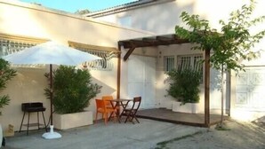 An outdoor patio area with a pergola, a table with chairs, and potted plants. - Holidays in the center of Corsica (Corte)