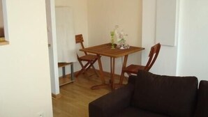 A room with a wooden dining table, two chairs, a dark sofa, and a white door. - Holidays in the center of Corsica (Corte)