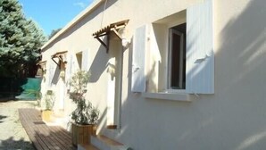 A building with white exterior walls, a wooden deck, and potted plants. - Holidays in the center of Corsica (Corte)