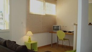 A small, well-lit room with a single bed, a desk with a computer, a chair, and a lamp. - Holidays in the center of Corsica (Corte)