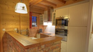 A kitchen with a stone island, wooden cabinets, and a built-in oven.