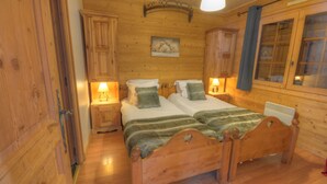A wooden room with two beds, wooden cabinets, and a painting on the wall.