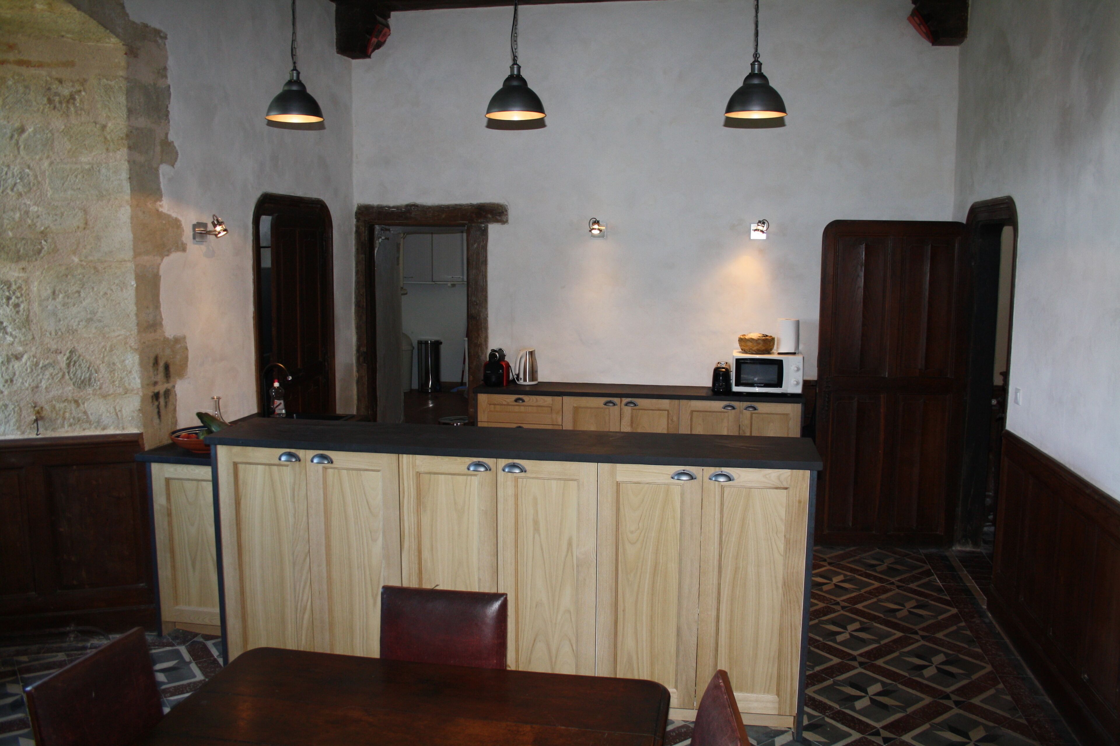 A kitchen with wooden cabinets, a central island, pendant lighting, and a patterned floor.