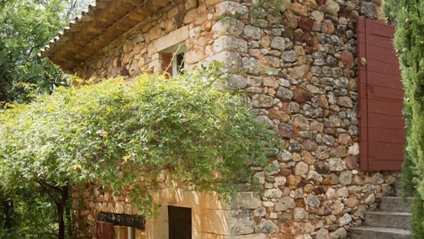 A stone building with a wooden door and steps leading up to it.