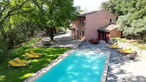 A rectangular swimming pool with a stone border, surrounded by a grassy area with yellow lounge chairs.