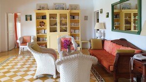A cozy living room with wicker furniture, a checkered floor, and a bookshelf filled with books.