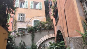 A narrow alleyway with buildings on either side, featuring balconies with potted plants and flowers. - RARE CHARMING APARTMENT IN OLD NICE, WITH A GARDEN VIEW, CLOSE TO THE SEA (Nice)
