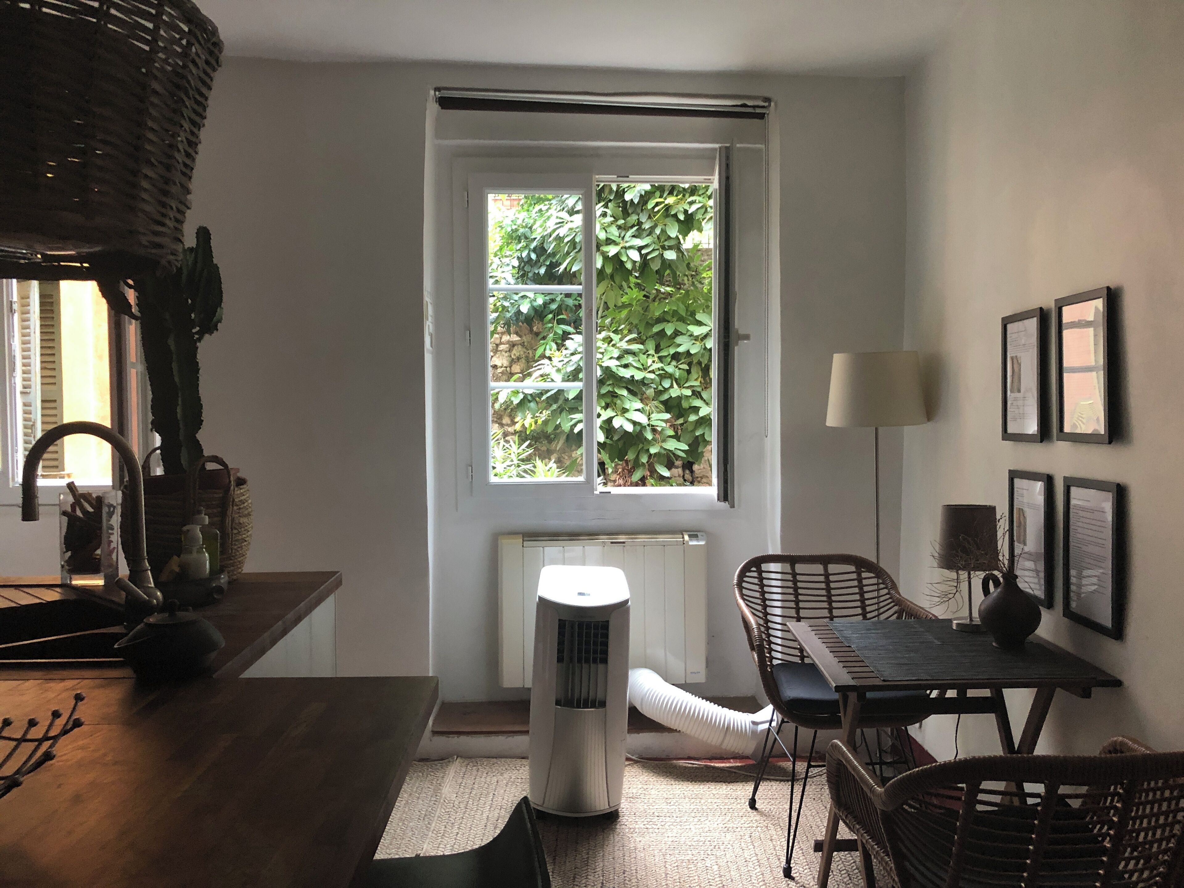 A room with a window, a radiator, a table, chairs, and a lamp.