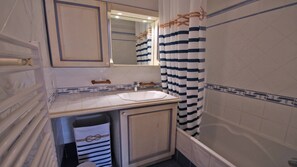 Un bagno con un lavandino bianco, uno specchio sopra e una tenda da doccia a righe.