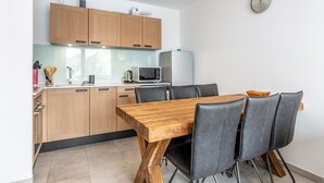 A modern kitchen with wooden cabinets, a microwave, and a dining table with chairs. - Modern apartment in Plagne Centre with balcony, 2 bedrooms and Wifi (La Plagne)