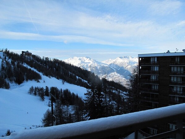 A hotel with a view of snow-covered mountains and a forested slope.