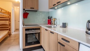 A modern kitchen with wooden cabinets, a built-in oven, a sink, and a kettle. - Modern apartment in Plagne Centre with balcony, 2 bedrooms and Wifi (La Plagne)