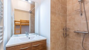 A bathroom with a wooden vanity, a large mirror, and a shower area. - Modern apartment in Plagne Centre with balcony, 2 bedrooms and Wifi (La Plagne)