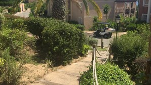 A residential area with a dirt path, palm trees, and a parked golf cart. - Cap Esterel (St Raphaël) - Quiet apartment with sea view, golf & Cap Esterel 4 pers. (Saint-Raphaël)