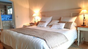A neatly made bed with a knitted throw, two bedside lamps, and pillows with text.