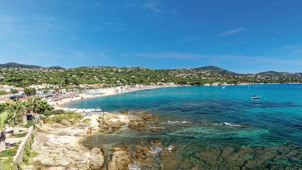 Une ville côtière dotée d’une plage, d’eaux cristallines et bordée de montagnes.