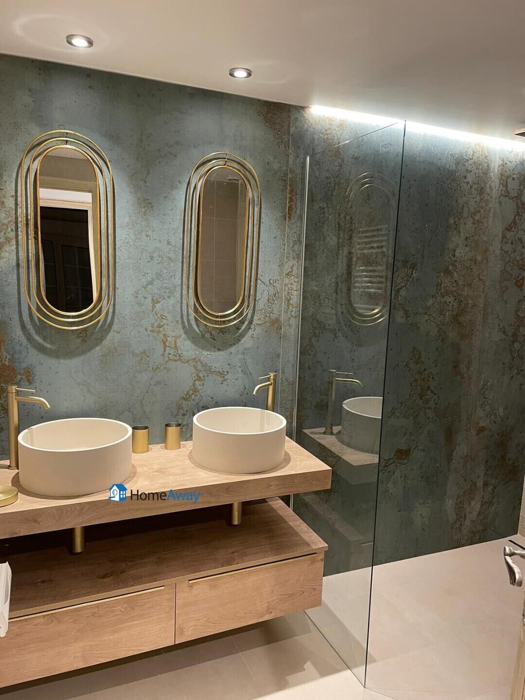 A modern bathroom with two sinks, a wooden vanity, and a large mirror.