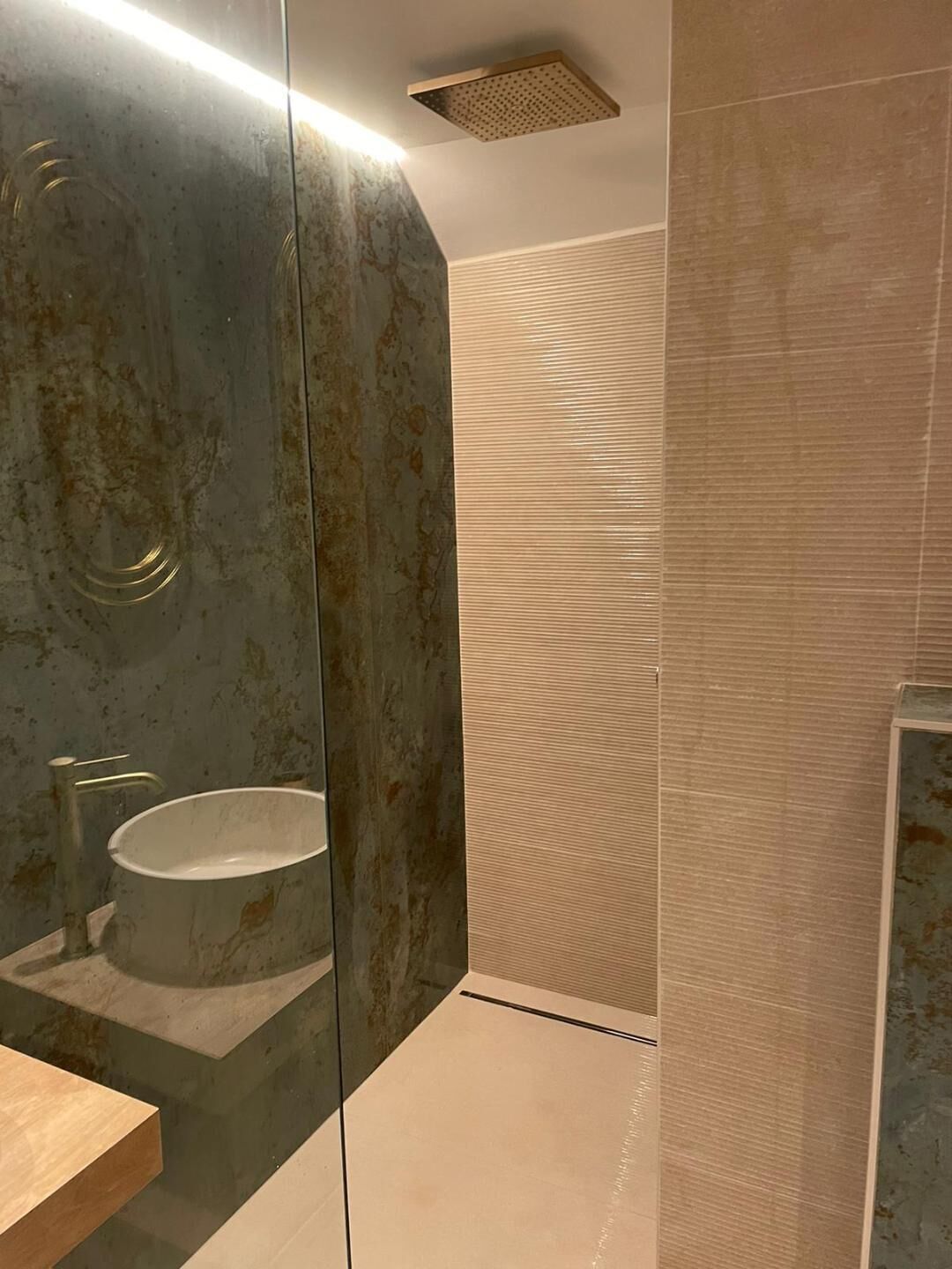 Une salle de bain avec un grand miroir, un lavabo et un espace douche.