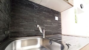 Et køkken med en stålvask, backsplash i sort marmor og en træbordplade.