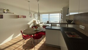 Una cocina moderna con comedor, ventanas amplias y vista al océano.