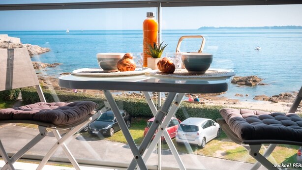 Balcón con mesa listo para el desayuno y vista al mar.