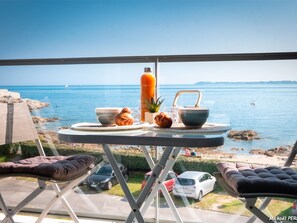 Un balcon avec une table dressée pour le petit-déjeuner, offrant une vue sur la côte.