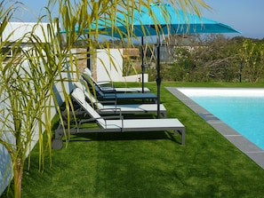 Relax by the pool surrounded by lush greenery and a well-maintained lawn.