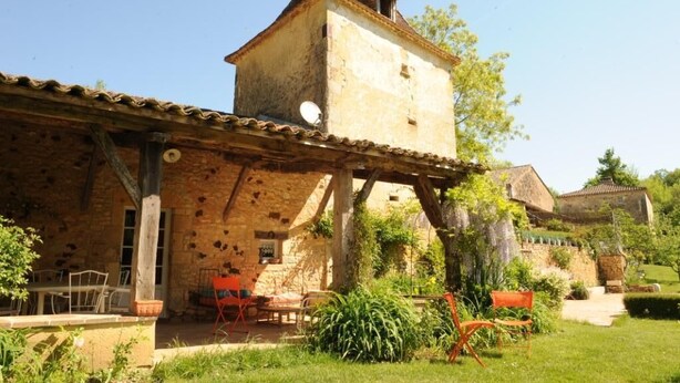 A rustic stone building with a tower, outdoor seating, and a garden. - Charming gîte well restored real comfort (Paulhiac)