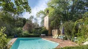 A rectangular swimming pool surrounded by lush greenery and a stone building. - Charming gîte well restored real comfort (Paulhiac)