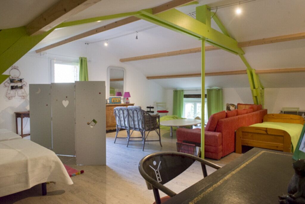 A cozy, well-lit room with a wooden ceiling, a dining table, a sofa, and a bed.