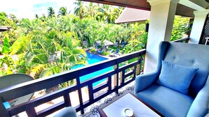 Un balcon avec une piscine, entouré d’une végétation luxuriante et de palmiers.