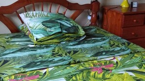 A bed with a wooden headboard, a canopy, and a floral bedspread. - Villa F3 in SAINTE-MARIE (SAINTE-MARIE)