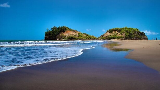 A beach with clear blue water, sandy shore, and two small hills with greenery. - Villa F3 in SAINTE-MARIE (SAINTE-MARIE)