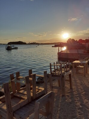 A wooden deck with chairs overlooking a calm body of water during sunset.