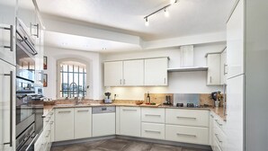 Een moderne keuken met witte kastjes, een inbouwoven en een groot raam dat voor natuurlijk licht zorgt.