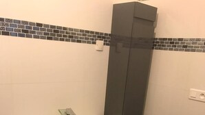 Un baño con lavamanos blanco, muebles oscuros y salpicadero de azulejos.