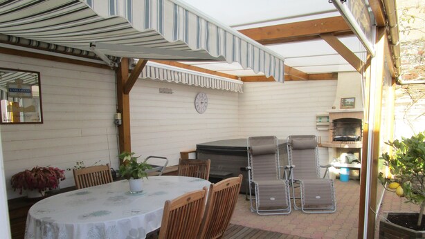 An outdoor patio with a round table, wooden chairs, a grill, and a clock on the wall. - Charming new house in downtown Les Sables D¥Olonne  (Les Sables d'Olonne)